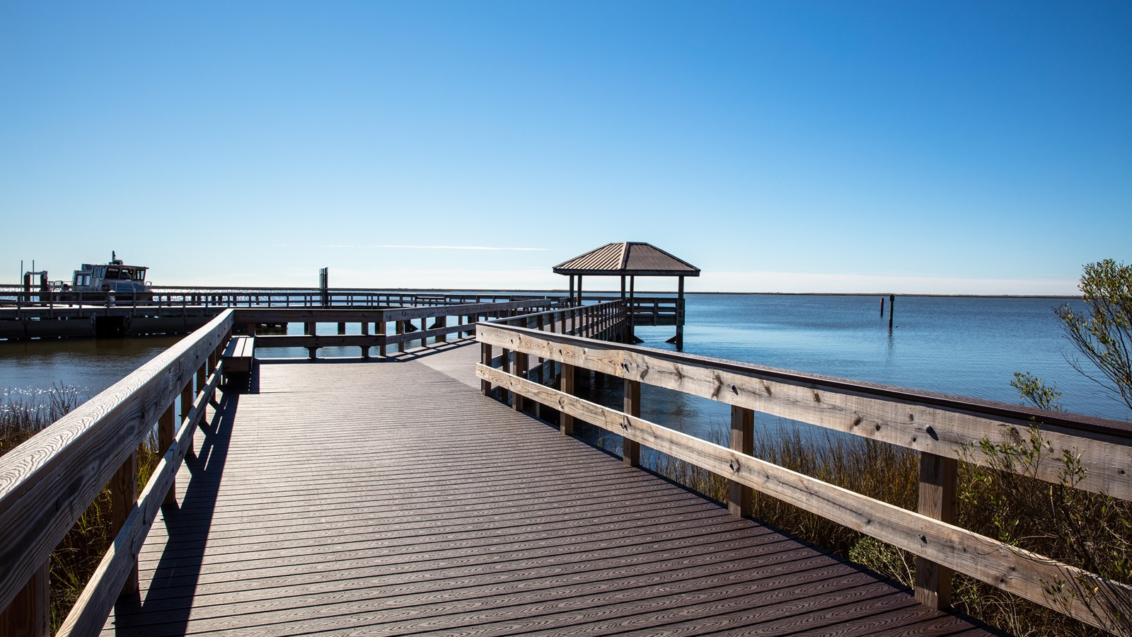 A wooden boardwalk stands over a blue bayou waterway