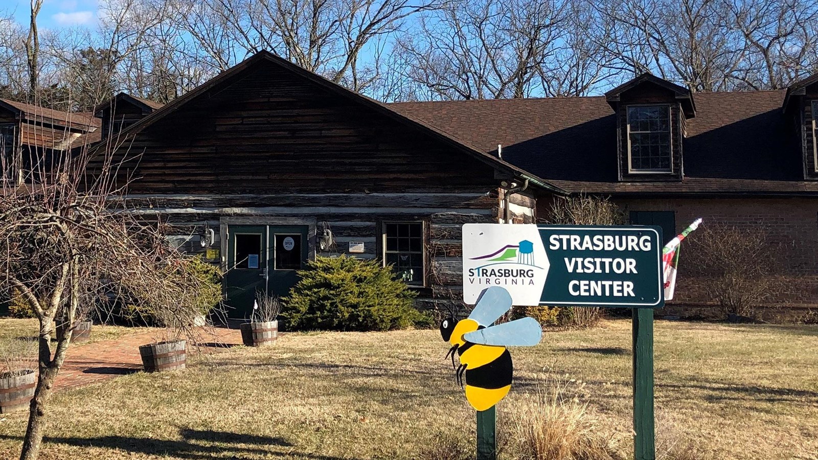 A sign in front of a rustic style building marks the Strasburg Visitor Center.