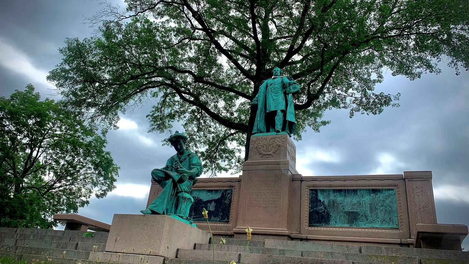 The Colt Memorial Statue nestled beneath an oak tree on a cloudy summer day. 