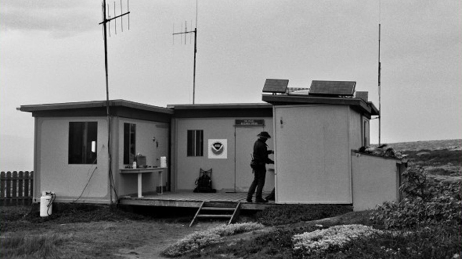 Person standing next to 3 shipping containers that have been converted to a station. 