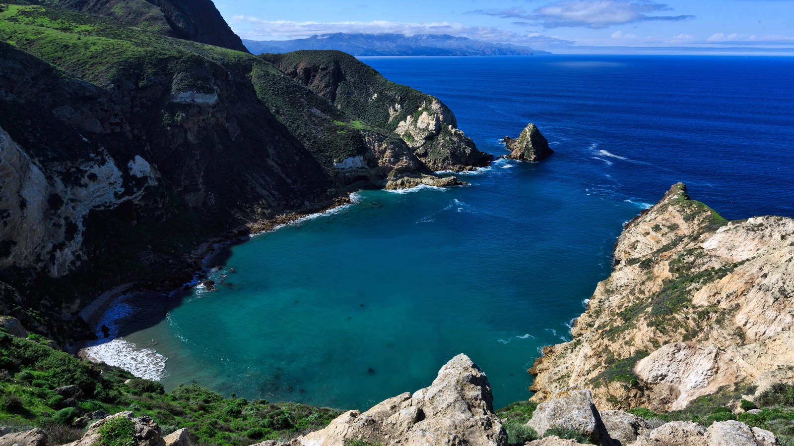 Narrow harbor in shape of a potato with tall cliffs surrounding it.