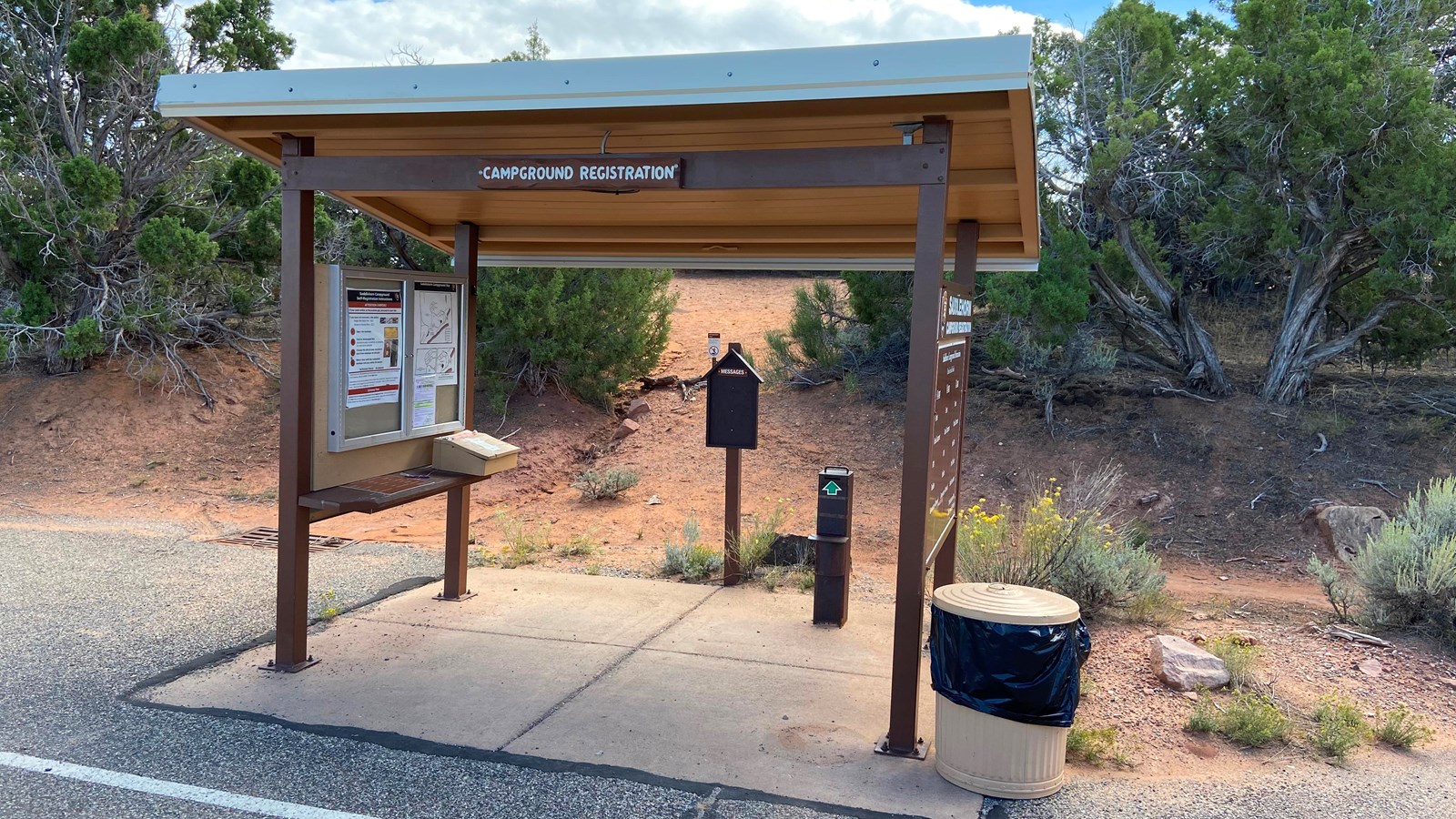 Structure with two sides and roof. Information boards regarding the campground are on each side.