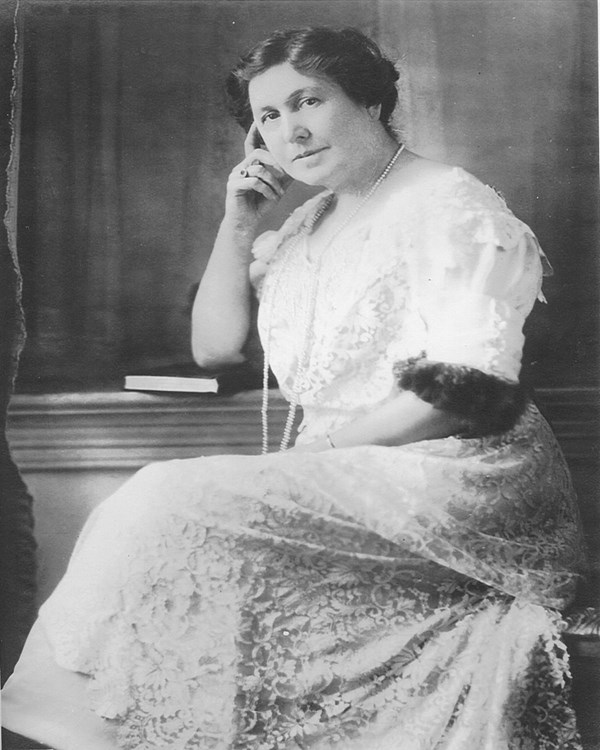 Black and white image of Josephine sitting in a white lace dress with elbow on a book