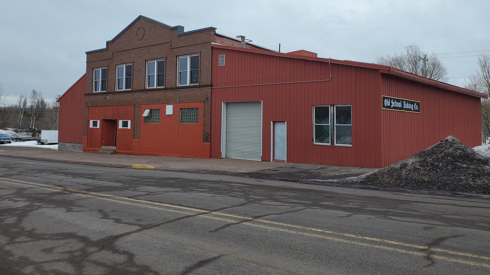 Two story building with red siding and gabled false-front roof.