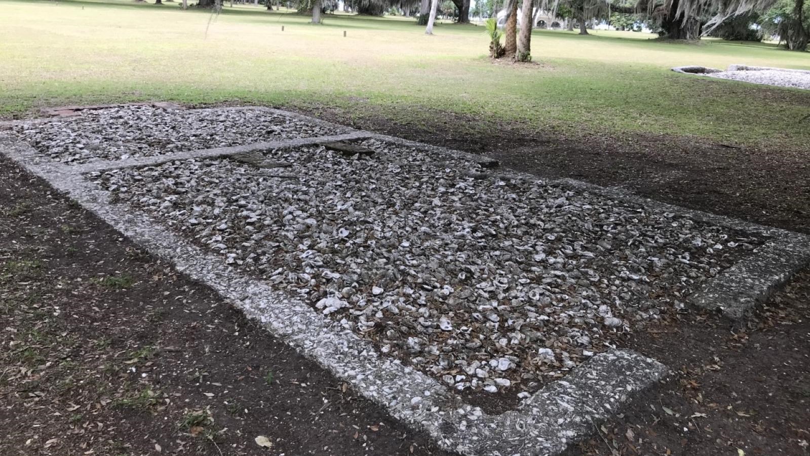Archaeological ruins of tabby concrete foundation surrounded by grassy area
