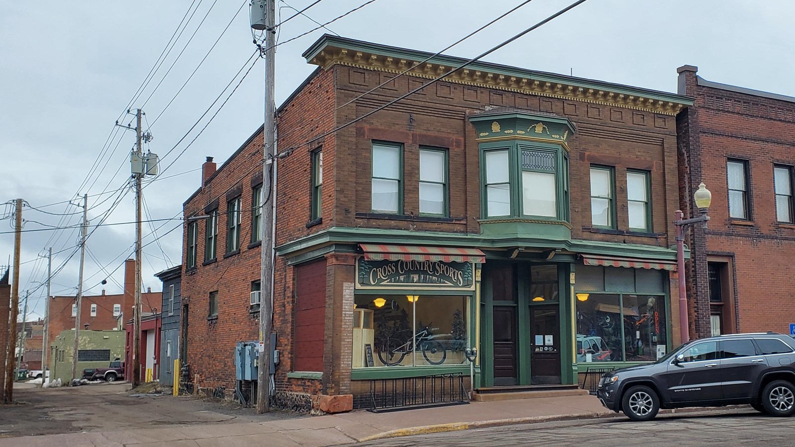 Two story red brick building with ornate storefront windows and green cornice.