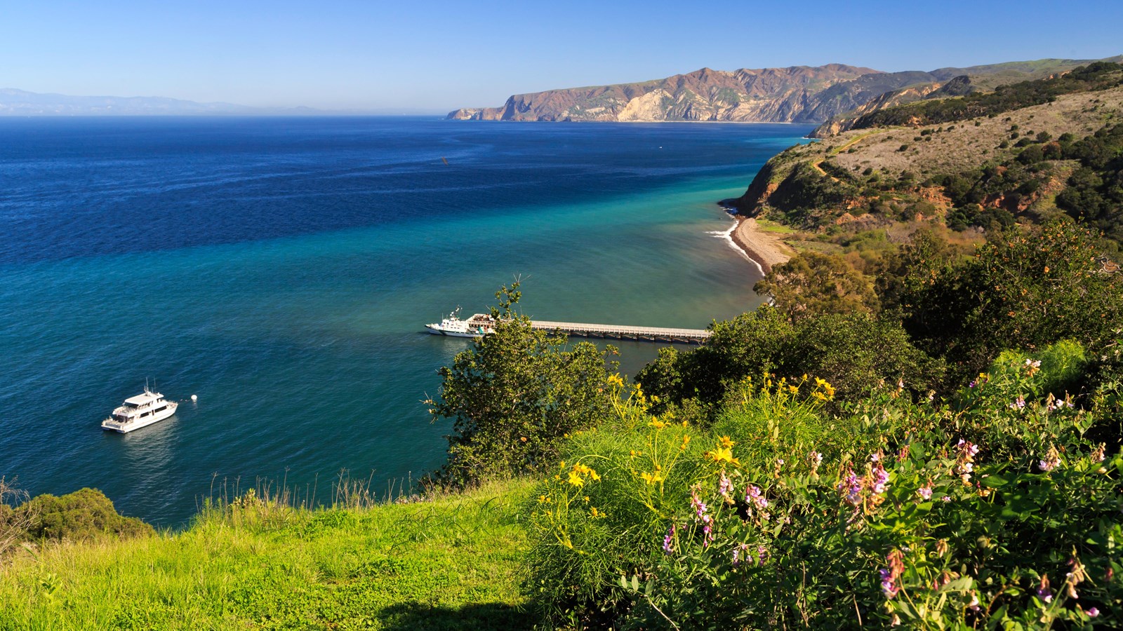 large bay with pier and boat and low ocean bluffs
