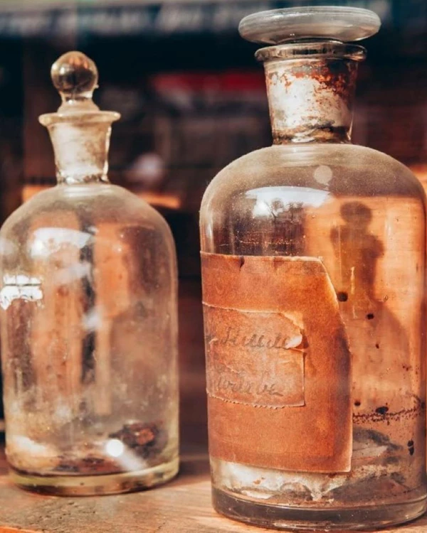 A close up of rustic clear glass medicine bottles on wooden shelf