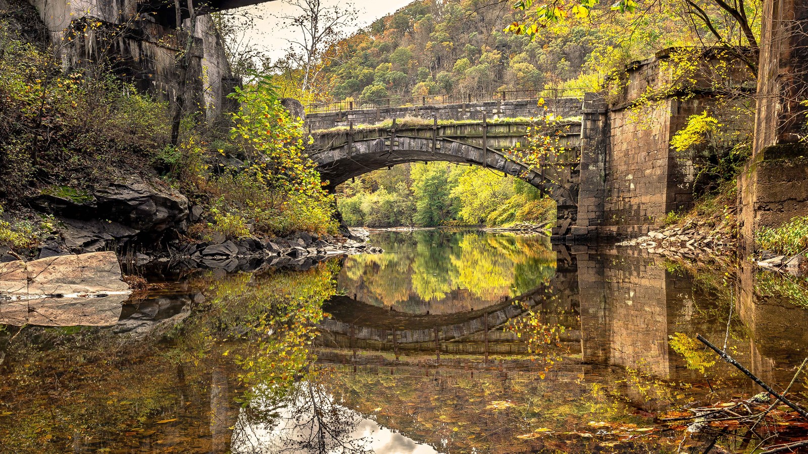 A single arch aqueduct spans a creek.