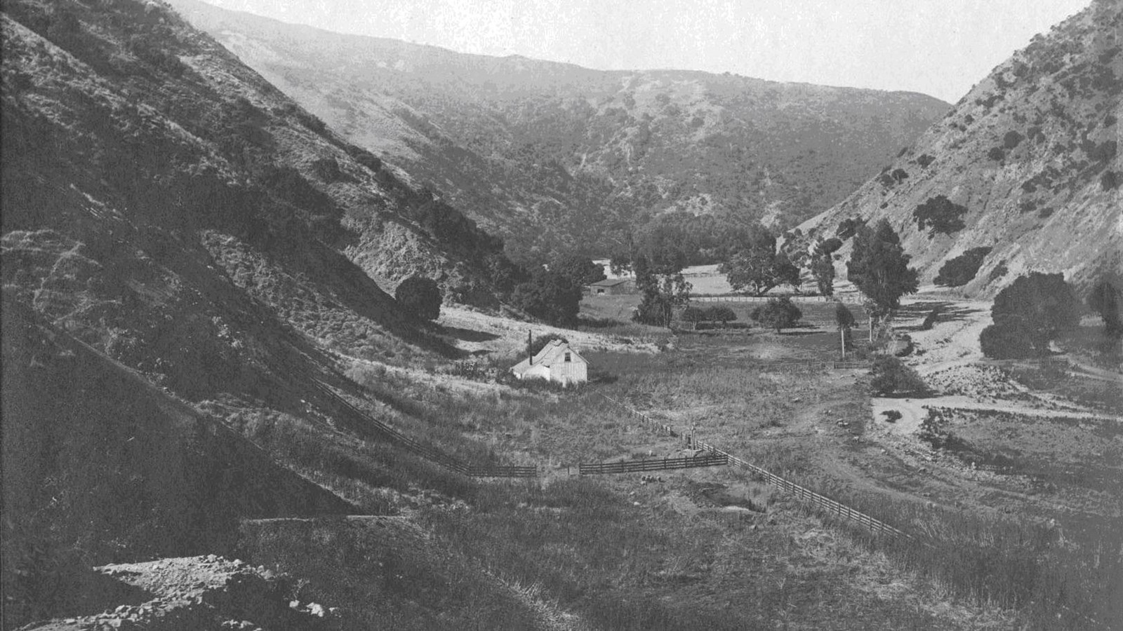 Valley with crop land and white building.