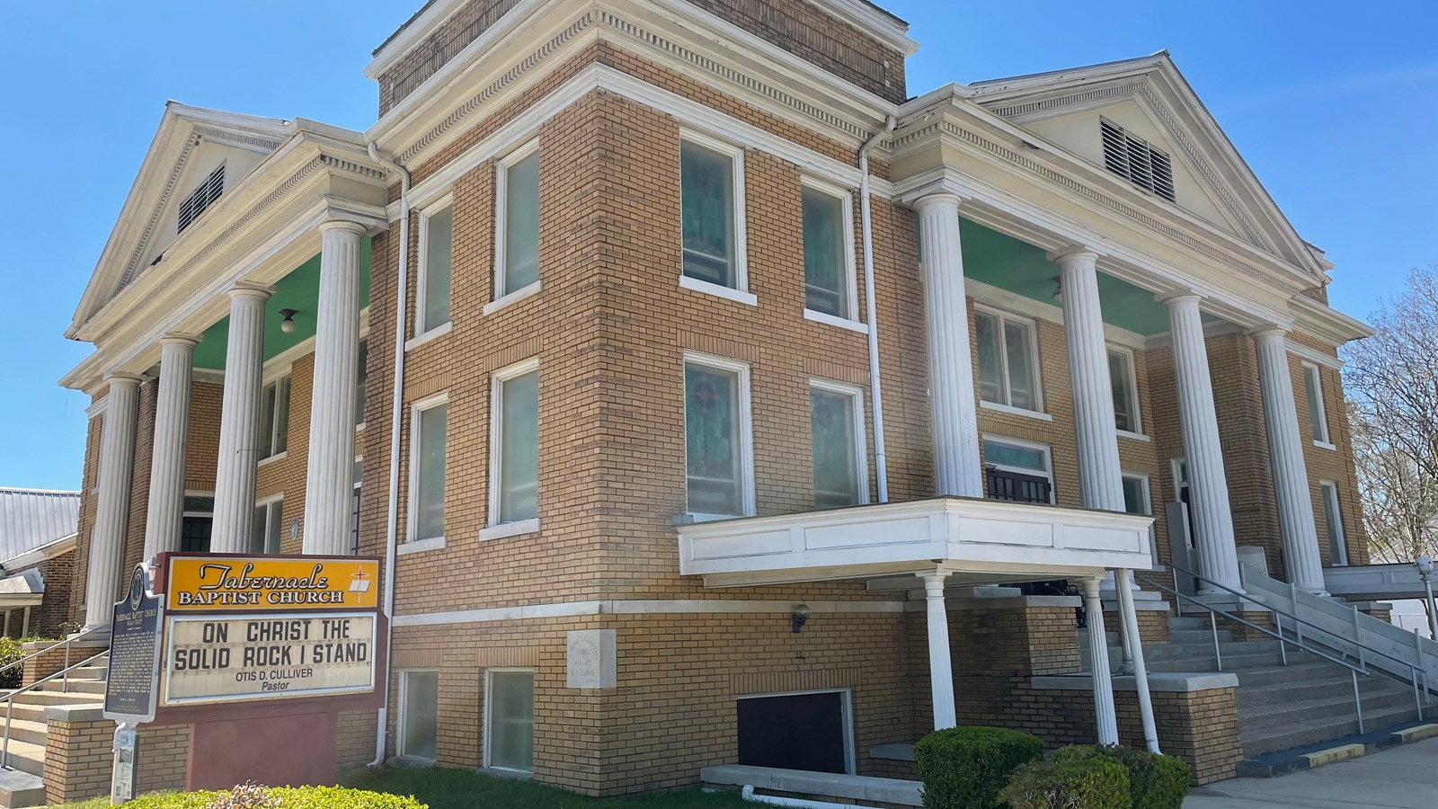 A two-story yellow-brick building with a rounded roof and brick pillars at the corners.