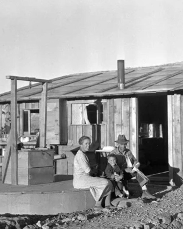 Black and white photo of a family in front of a wooden ranch house.