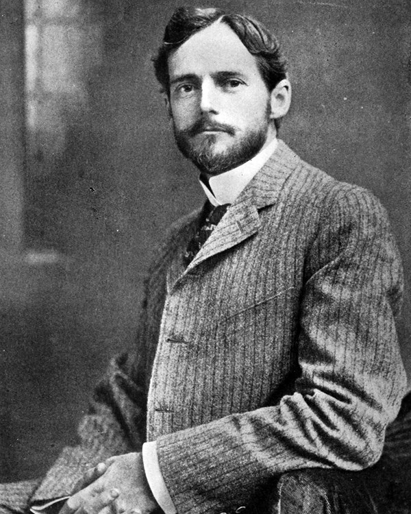 A black and white photograph of a white man with a mustache and beard, neatly trimmed.