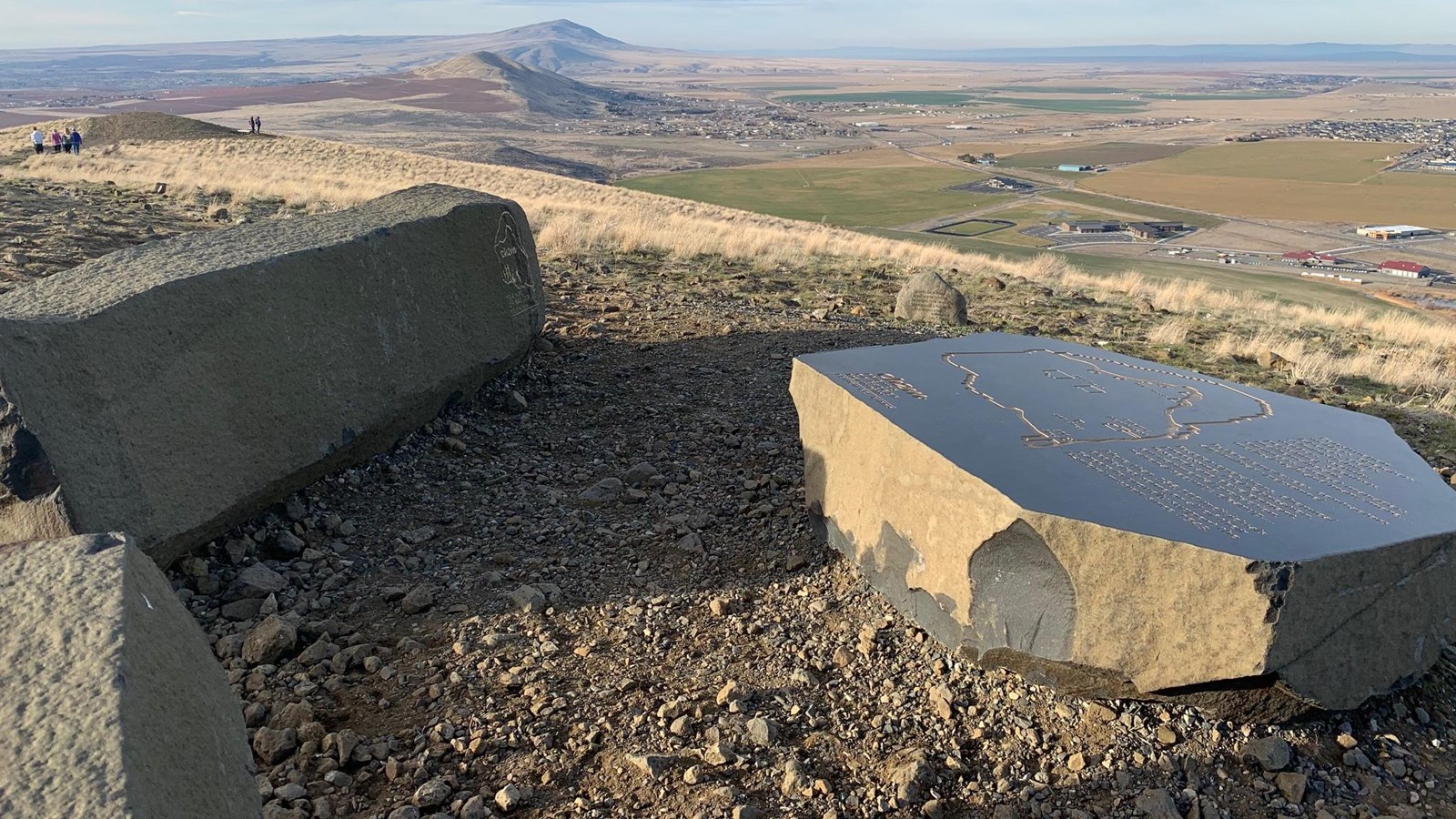 color photograph of a stone bench beside an inscribed stone and soaring view