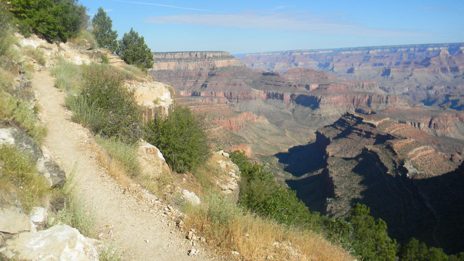 A rocky trail leads down into the depths of Grand Canyon along the side of a steep slope.
