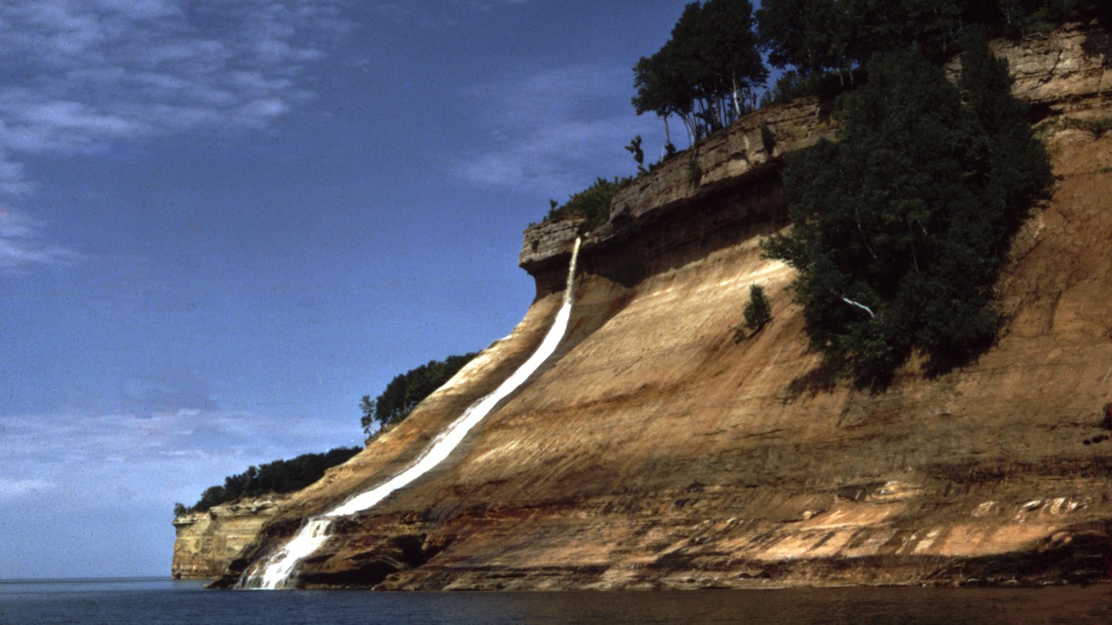 This waterfall flows vertically over a hard rock cap onto softer sandstone rock that slopes at a 4
