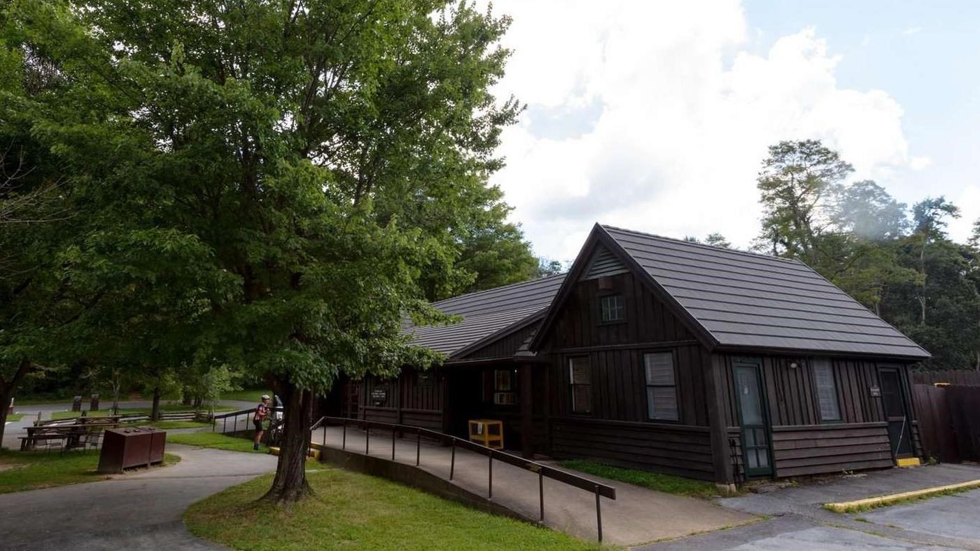 A photograph of a brown building with a walkway in the front and picnic tables outside.