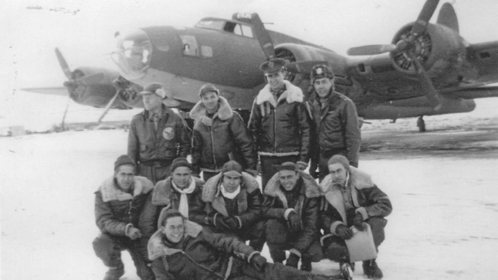 10 men in winter clothing in front of B-17 Bomber aircraft