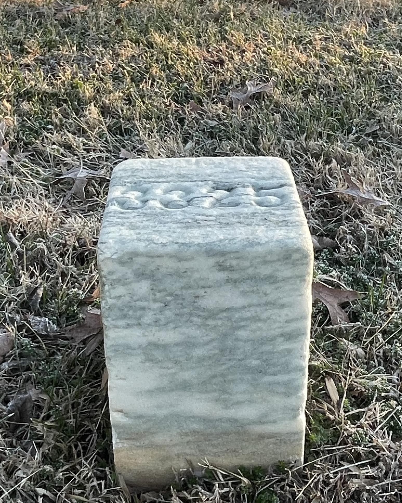 Short, square marble grave marker. 