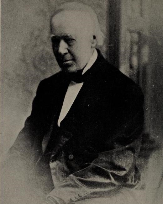 A black and white photo of an elderly man in 19th century formal wear.