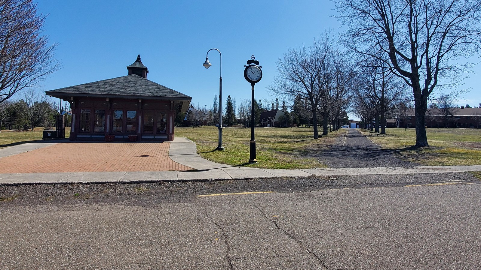 Spring scene of a grass park with walkway and line of trees running from the foreground to backgroun