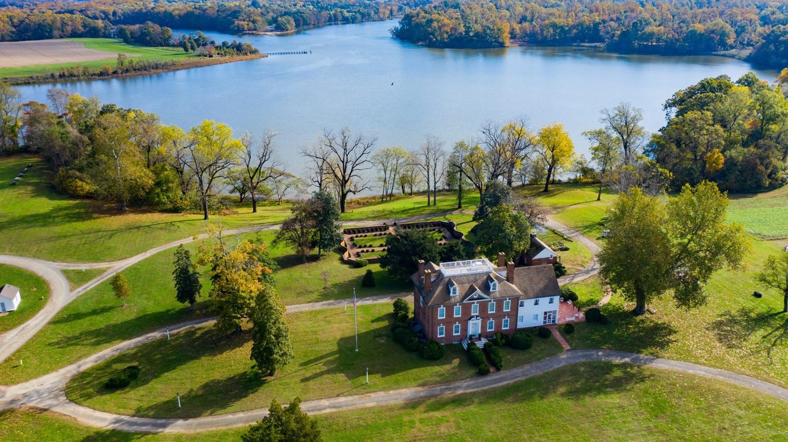 Aerial view of Mount Harmon Plantation\'s brick house, lawns, driveway, lake, and autumn trees.