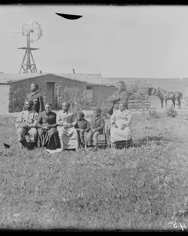 Family of 8 African Americans posing in front of sod house