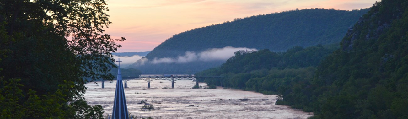 Jefferson Rock view at sunrise; pink in the sky and a light fog over a mountain gap and rivers