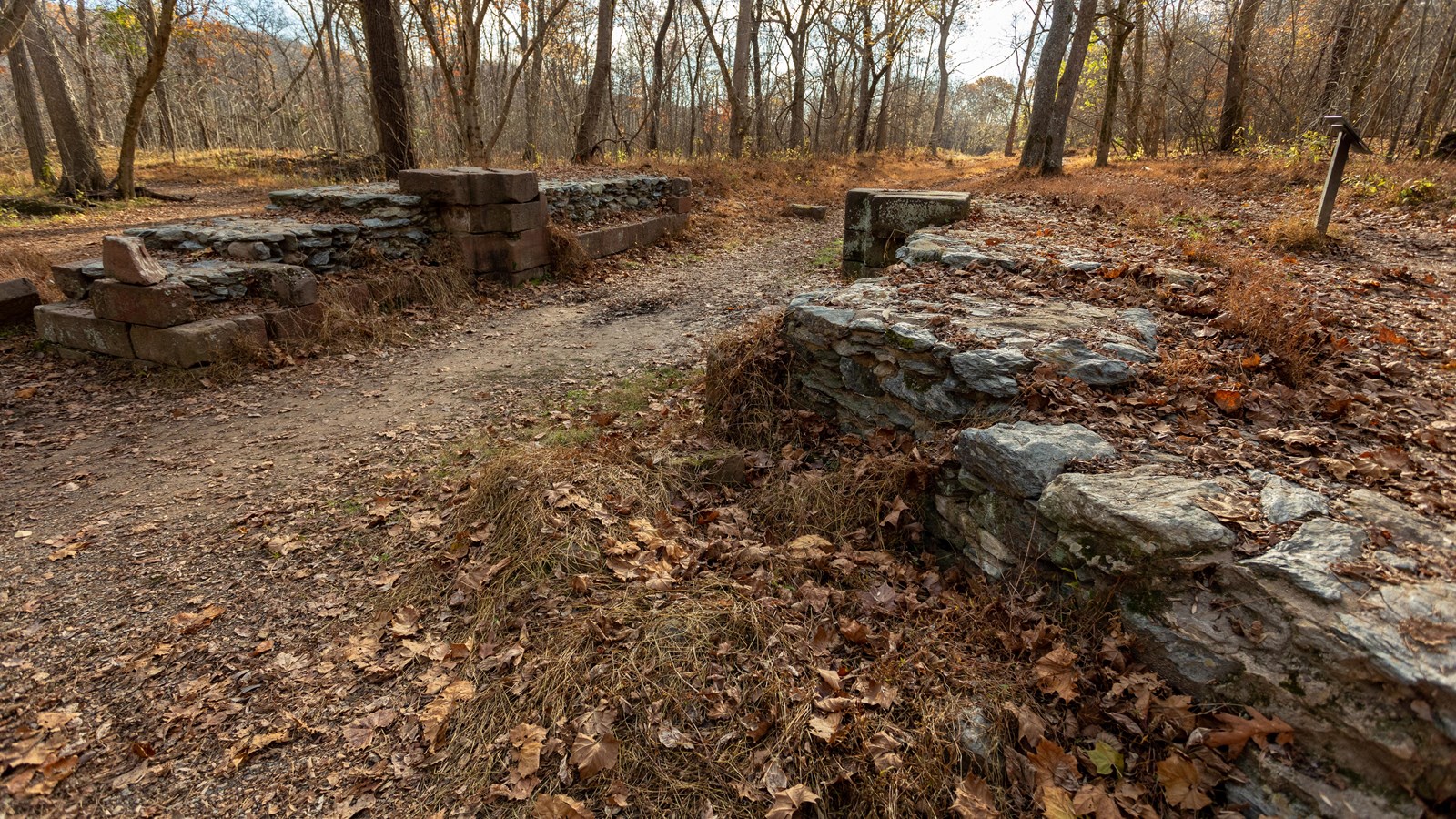 A dirt/gravel pathway is surrounded by short walls of rock on either side.