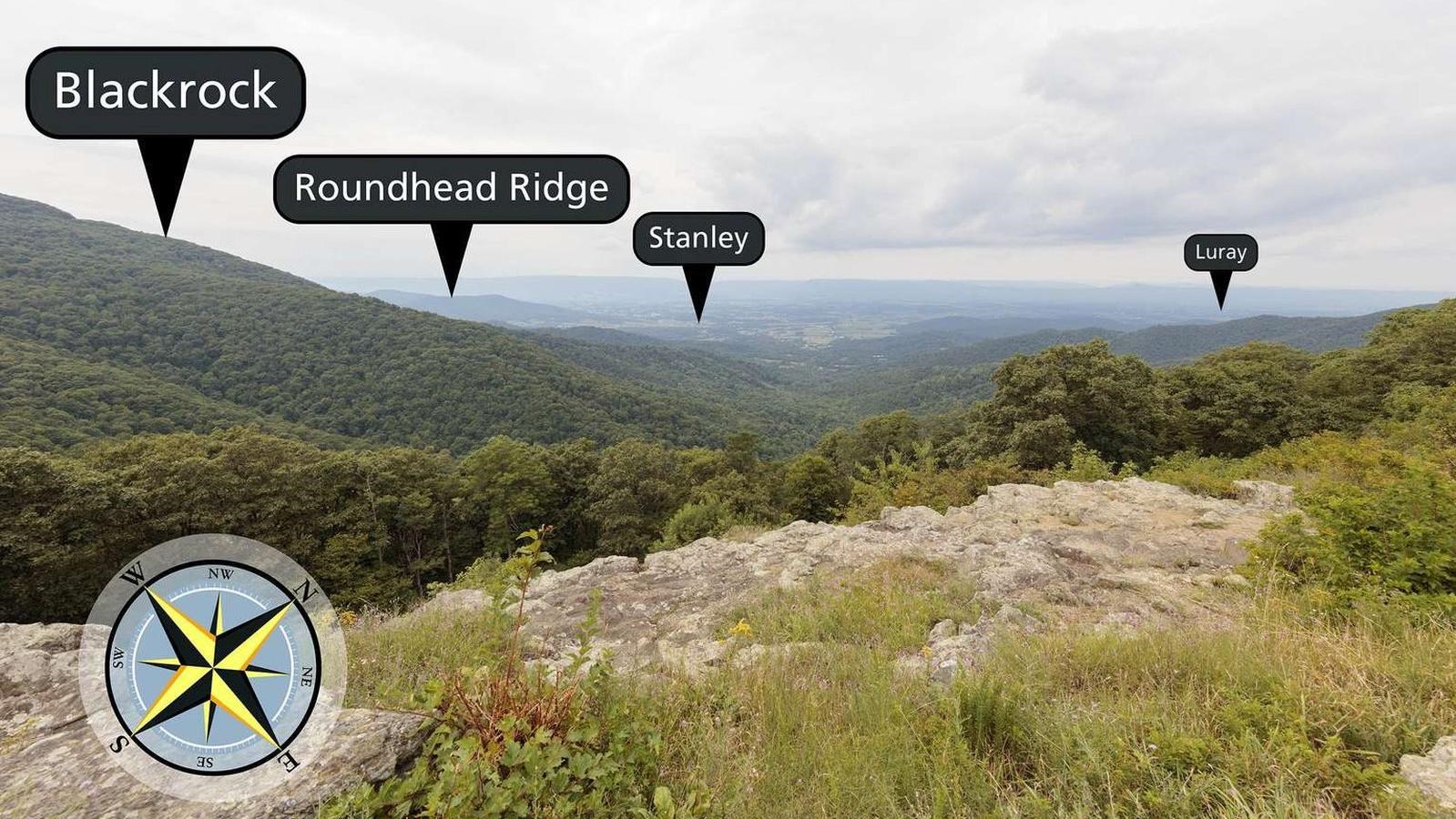 View over rocky ledge into foothills and valley below.