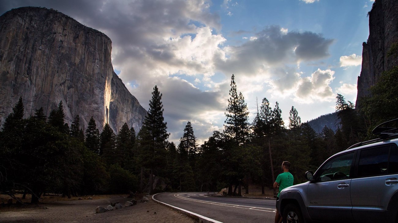 Car parked along Bridalveil Straight with El Capitan in view and a person leaning on the hood