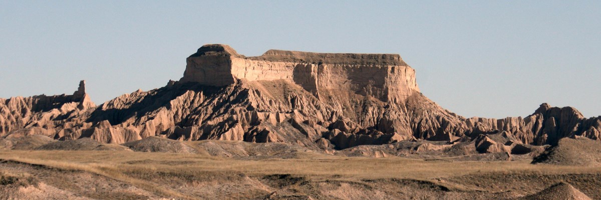 a large, flat table stands out from similarly brown badlands buttes.
