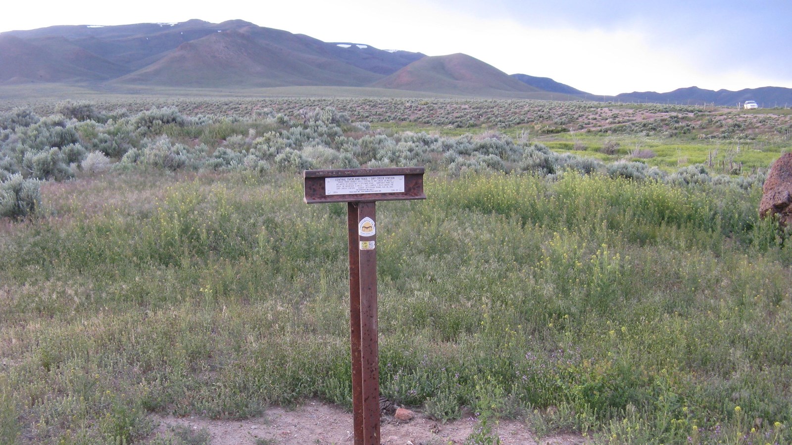 T-shaped post with plaque in yellow wildflowers; historic trail quote about Dry Creek Station, 1862.