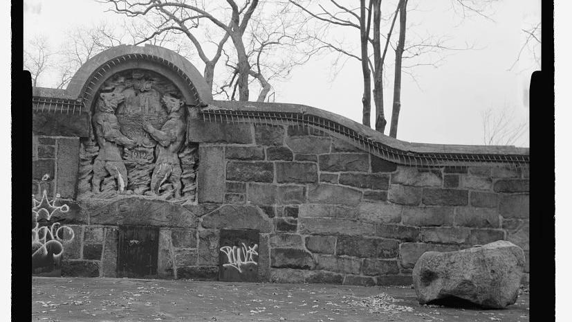 Black and white of stone wall with bear carving in it. 