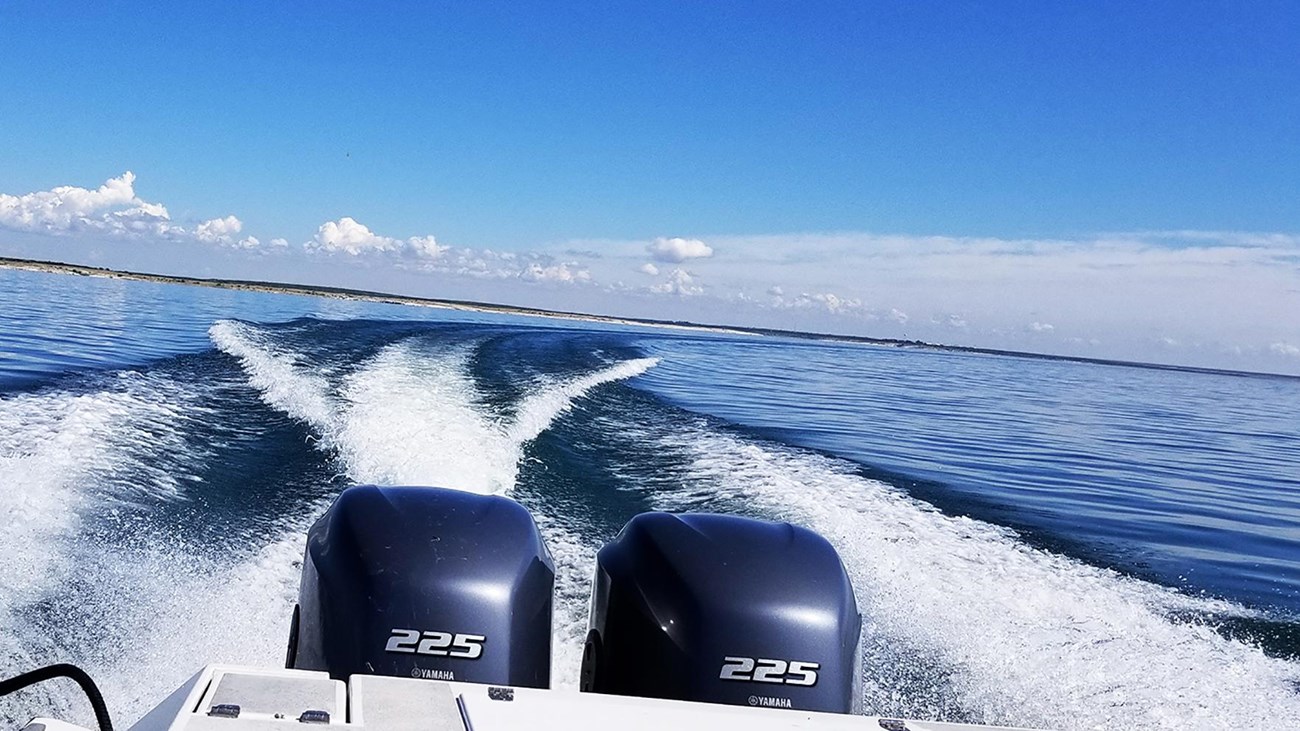 Back of motorboat looking out toward the horizon showing a banking turn to the starboard side.