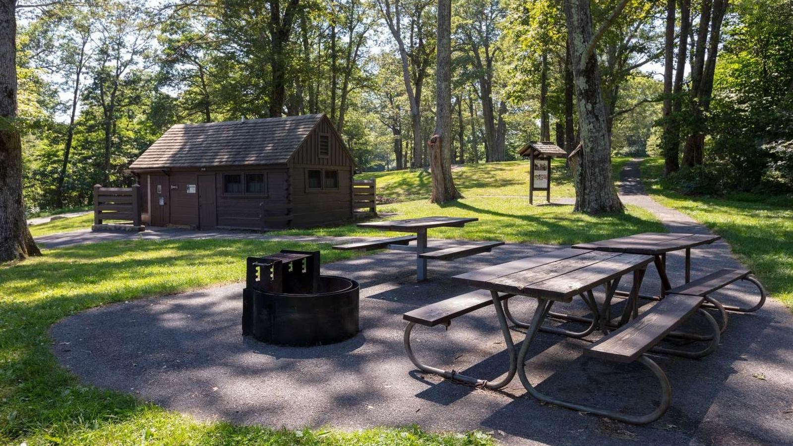 A picnic table on a concrete platform with a rectangular brown building in the background.