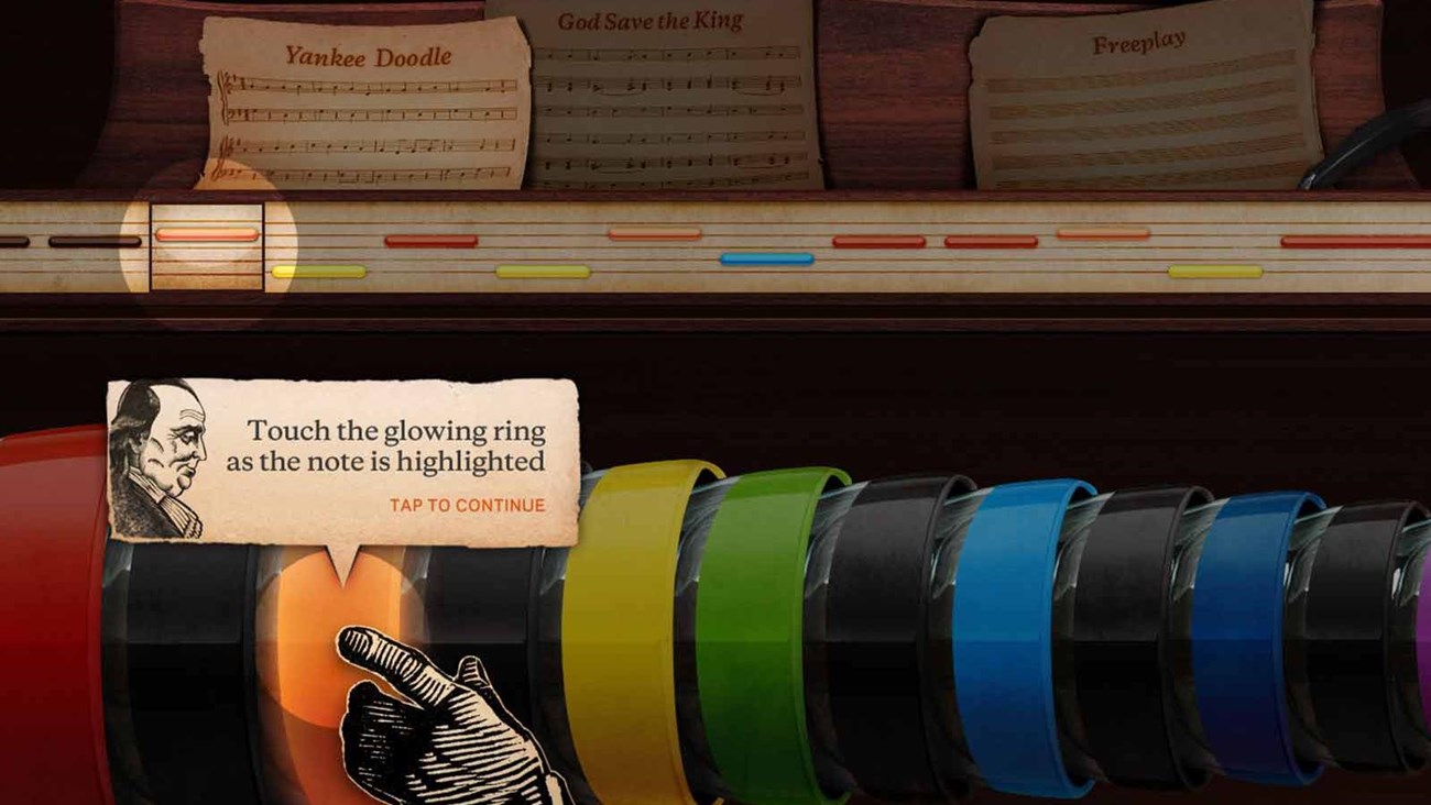 Screen shot of the glass armonica interactive, showing a hand reaching out to colored bowls.