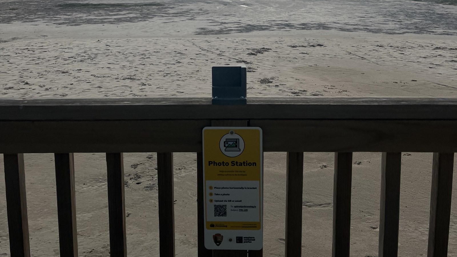 A photo monitoring station attached to a wooded railing. 
