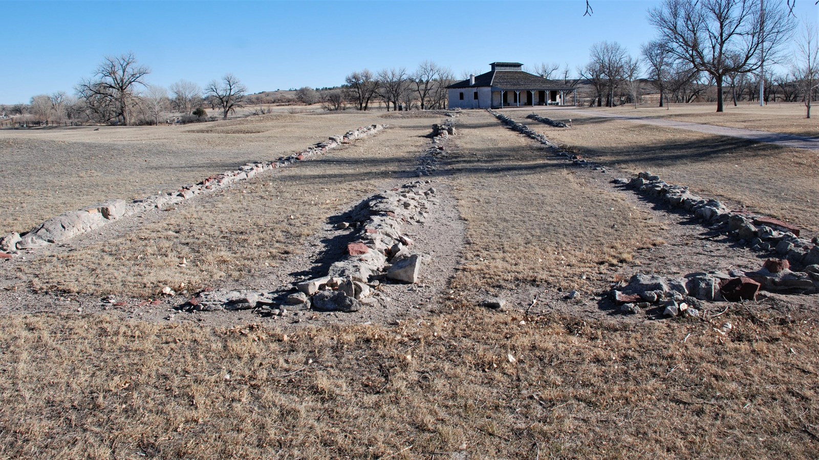 A low set of foundations with the New Guardhouse (1876) in the background.