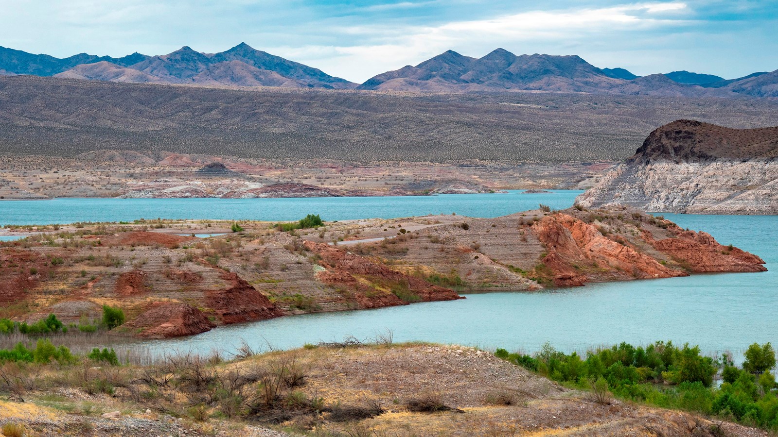 A mountainous landscape with a large body of water in the foreground