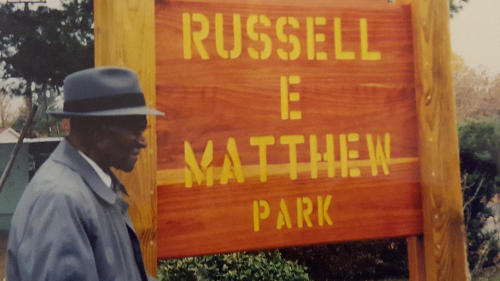 man with hat standing in front of park sign