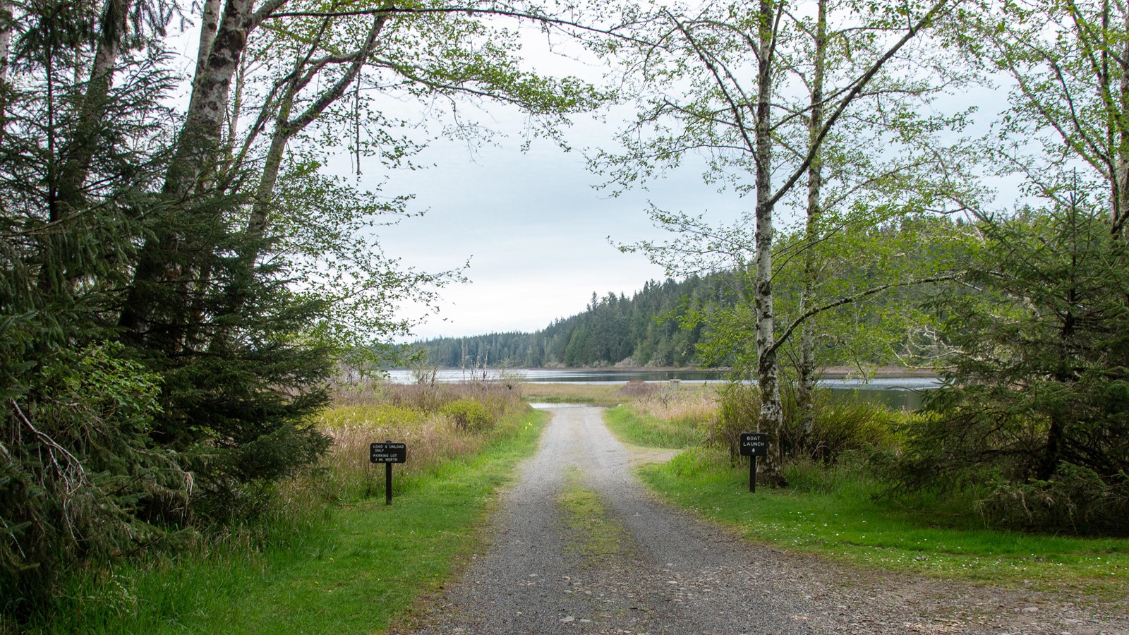 A dirt road slopes gently into a lake in the distance