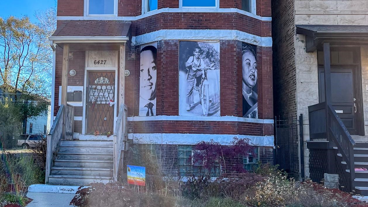 Exterior of a brick residential building with larhe black anmd white photos in the front windows