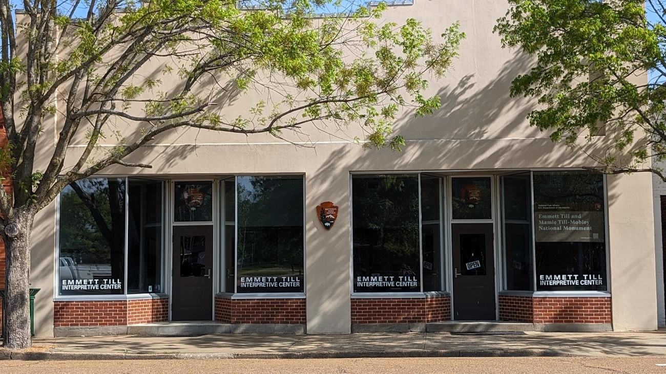 exterior of a tan building framed by two trees