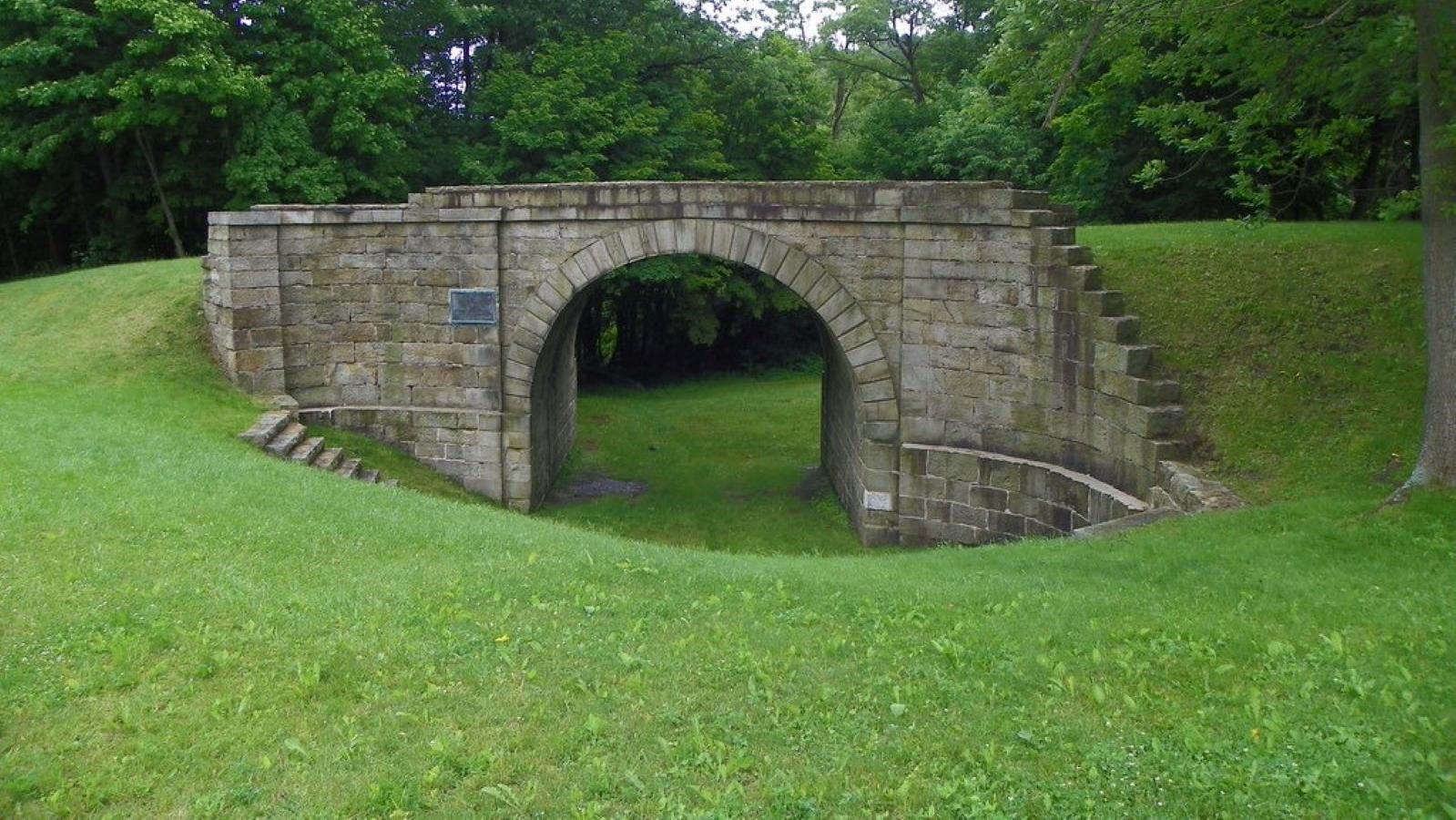 A stone railroad bridge built at an angle. 