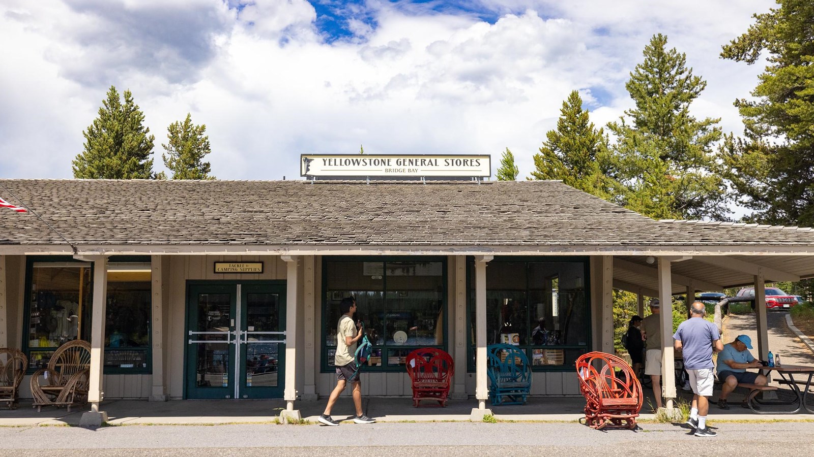 People hang out in the shade on the porch of a general store.
