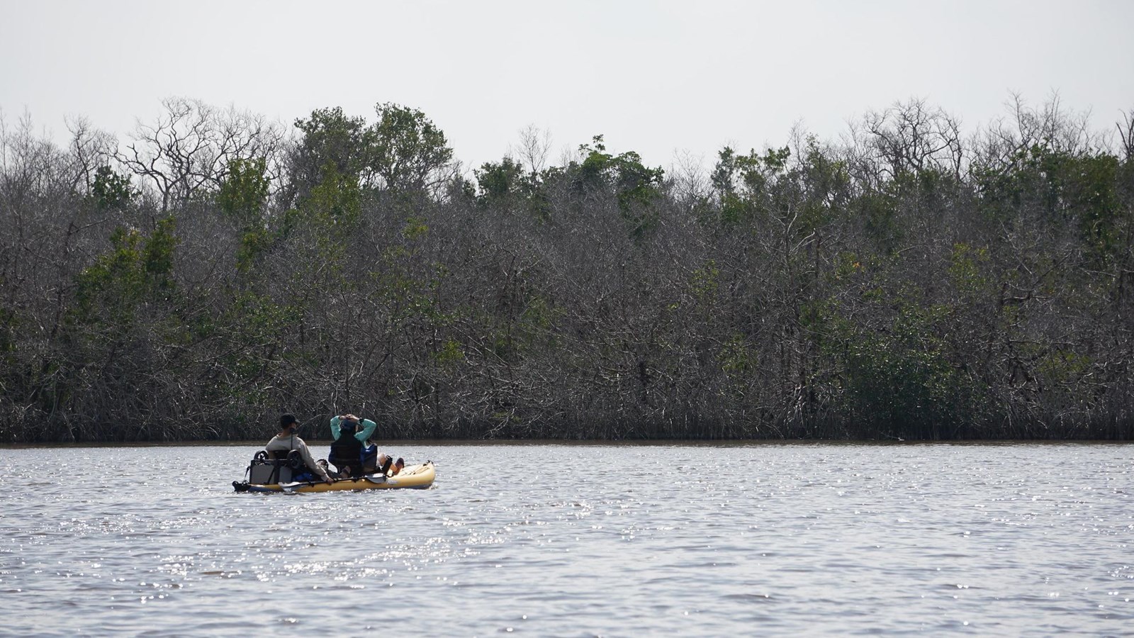 Kayakers in a yellow kayak relax on the sparkling blue waters of West Lake
