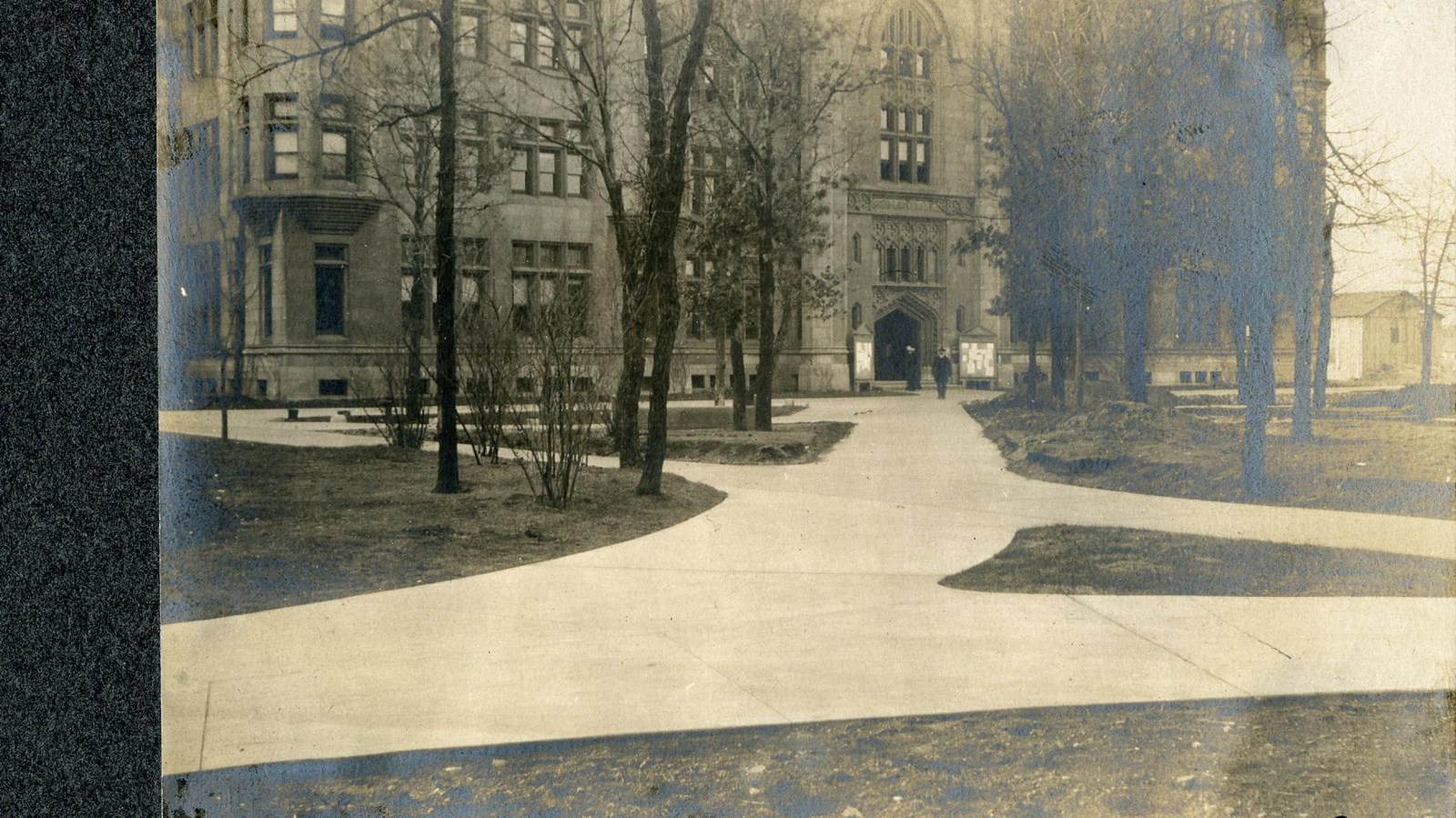 Black and white of paths long flat grassy area with trees along path leading to building