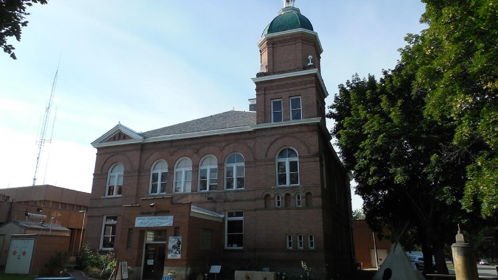 A two story brick house with a tower and white trimmed windows