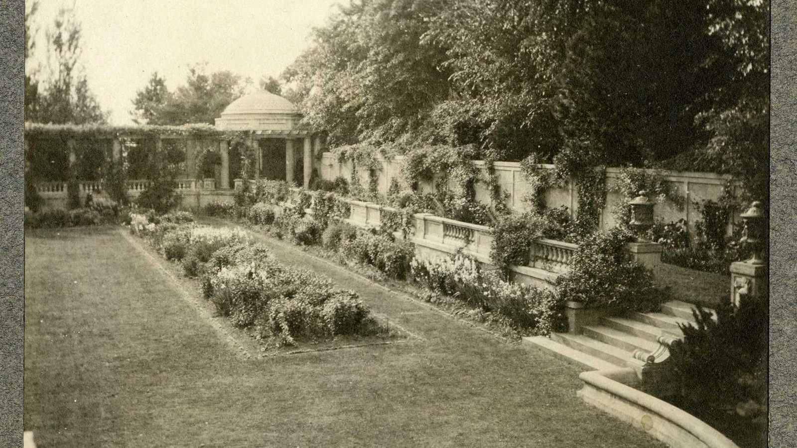 Black and white of garden with grassy area, shrub rectangular area, and elevated section with plants